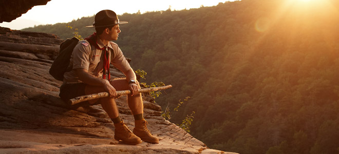 Scout resting on cliff at sunset